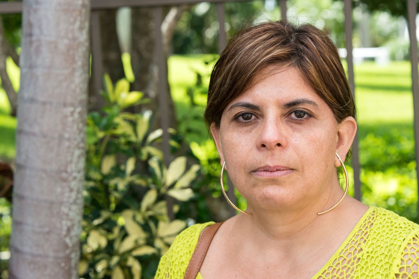 Middle aged woman in a yellow top standing in a park