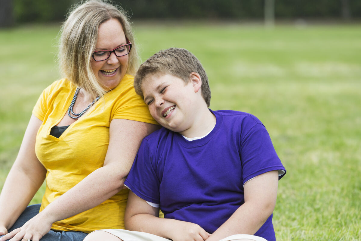 Mother and primary school child leaning on each other on the pitch